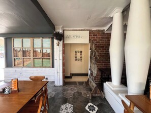 Un vestíbulo de hotel con una mesa de madera, un ventilador antiguo, una pared de ladrillo y un letrero que dice 'ATARA Hotel'.