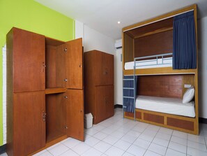 Una habitación con literas, armarios de madera y suelo de baldosas.