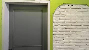 A door with a sign above it, a white brick wall, and a green painted wall.