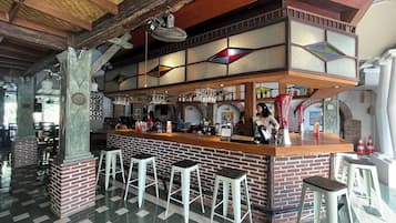 A bar area with a brick counter, stools, and hanging lights.