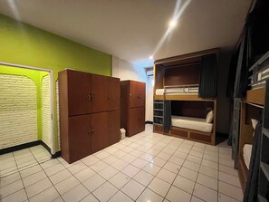 Una habitación con literas, un armario y suelo de baldosas.