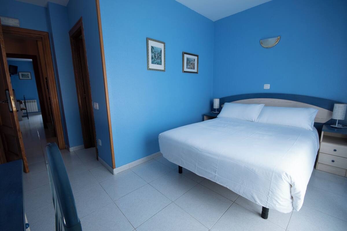Un dormitorio con una cama grande, una mesita de noche y dos cuadros en la pared.