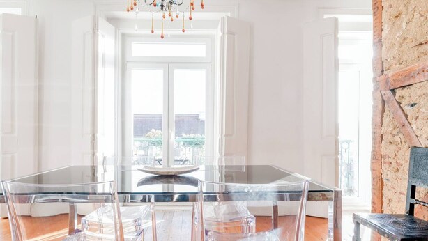A dining area with a glass table and chairs, a chandelier, and a view of the outdoors through large windows. - Eighteen21 Houses - Casa de São Paulo (Lisbon)