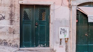 A building with a green door, a window with shutters, and a stone wall. - Eighteen21 Houses - Casa de São Paulo (Lisbon)