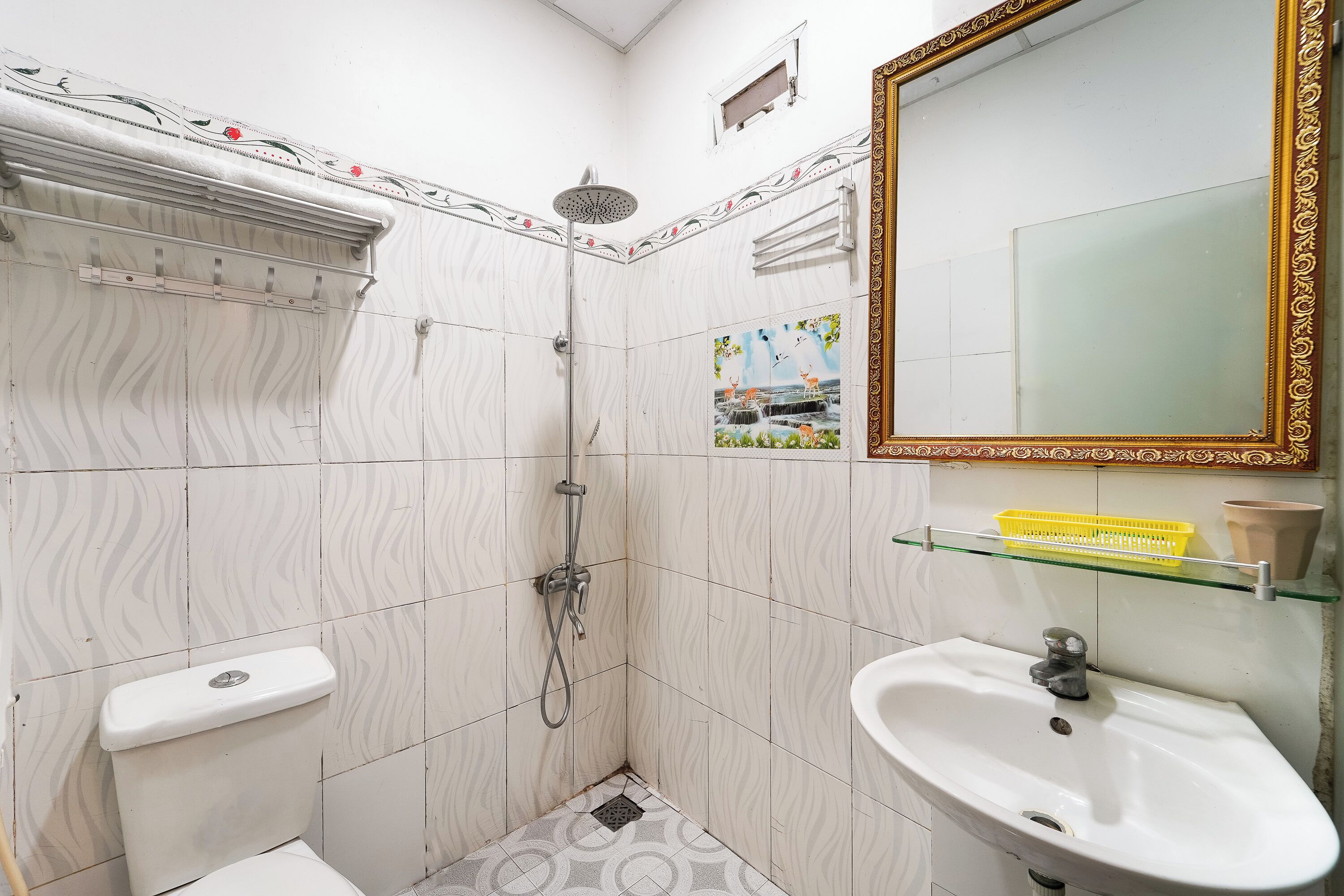 A bathroom with a shower, toilet, sink, and decorative tiles.