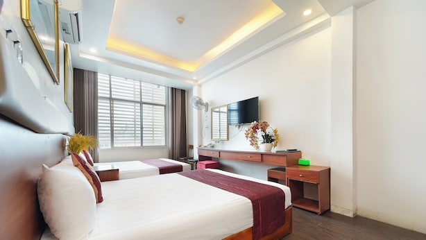 Una habitación de hotel con una cama grande, un escritorio con televisor de pantalla plana y una ventana con persianas.