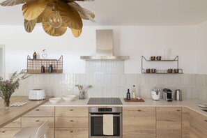 A modern kitchen with a wooden countertop, stainless steel appliances, and a hanging light fixture. - Maison Violette Paradou - pool - garden (Paradou)