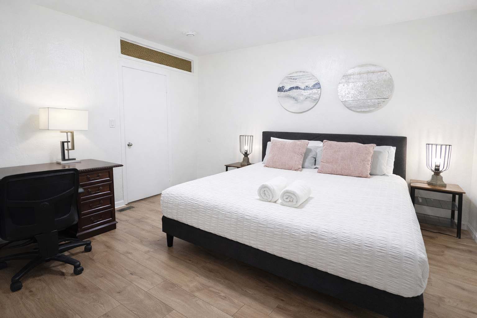 A bedroom with a large bed, two bedside tables, a desk, and a chair.
