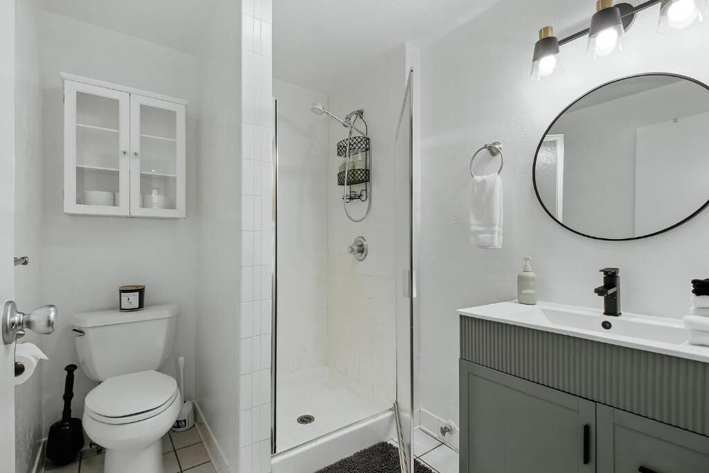 A bathroom with a toilet, a shower, a sink, and a cabinet.