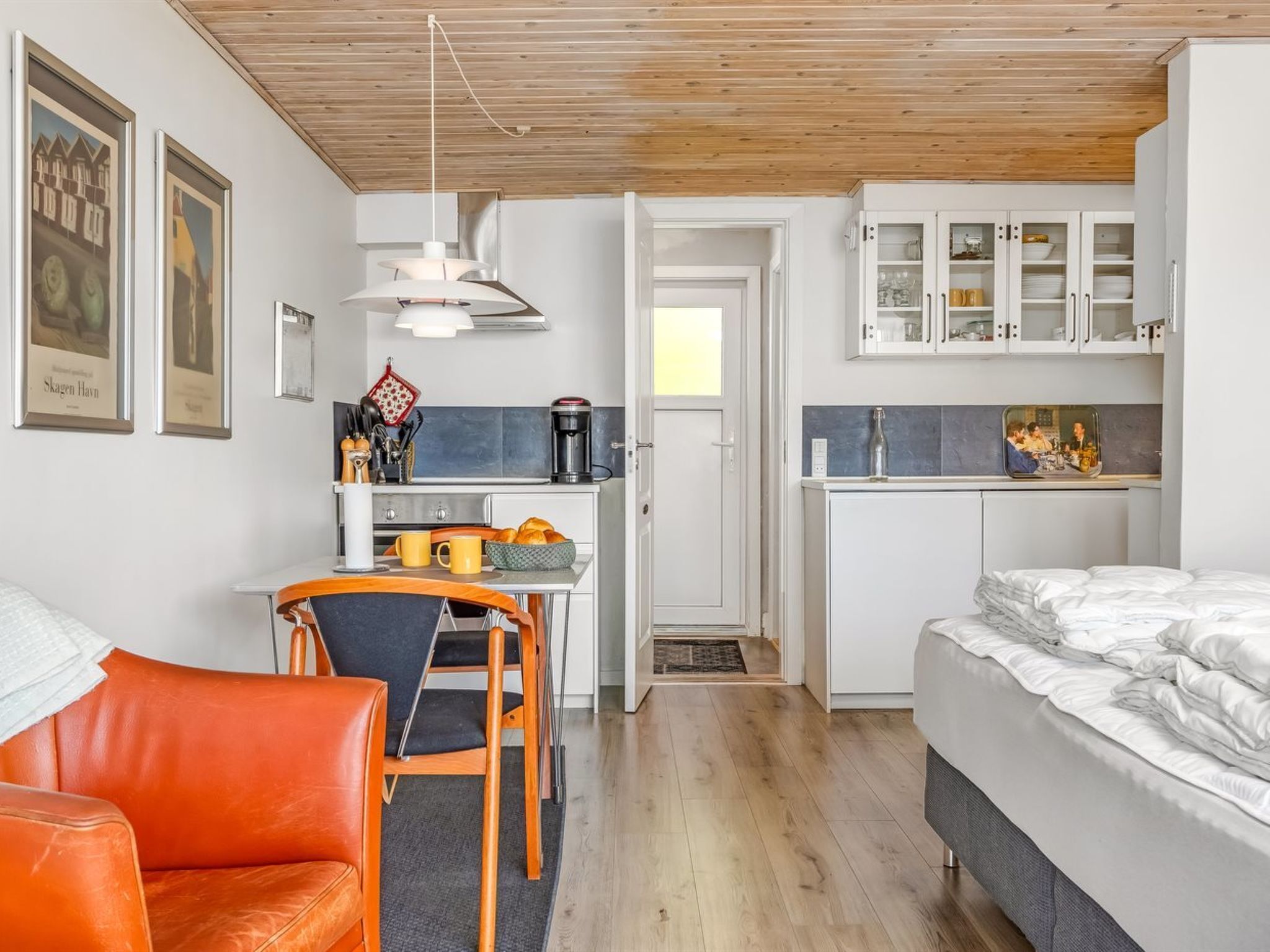 A compact room with a bed, a dining area, and a kitchenette.