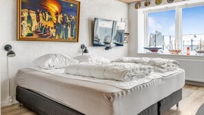 Une chambre à coucher avec un grand lit, un tableau, une télévision et une fenêtre donnant sur le port.