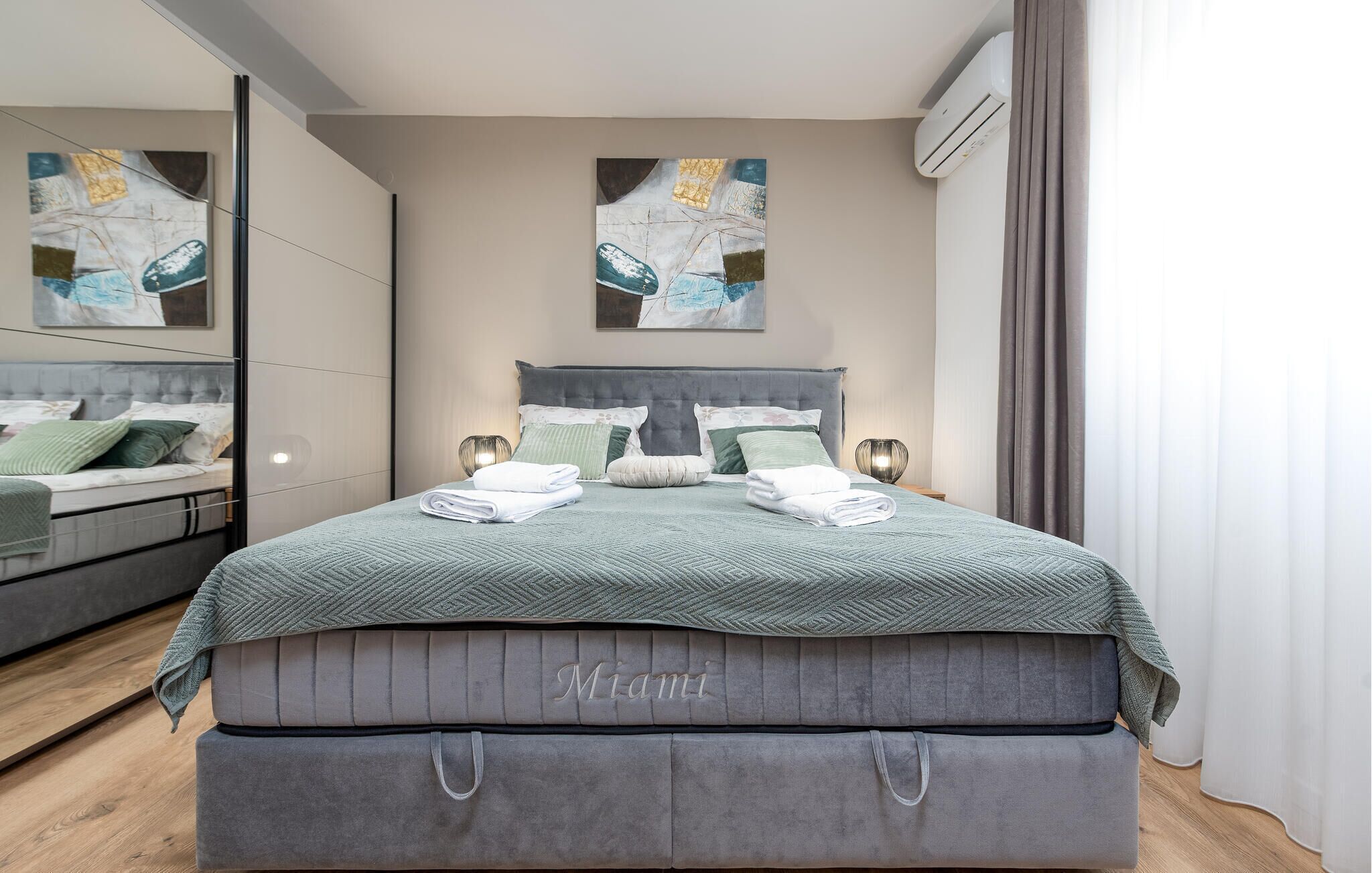 A modern bedroom with a large bed, a nightstand, and a mirror.