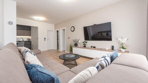 Un salon moderne avec un grand canapé, une table basse et un téléviseur fixé au mur.