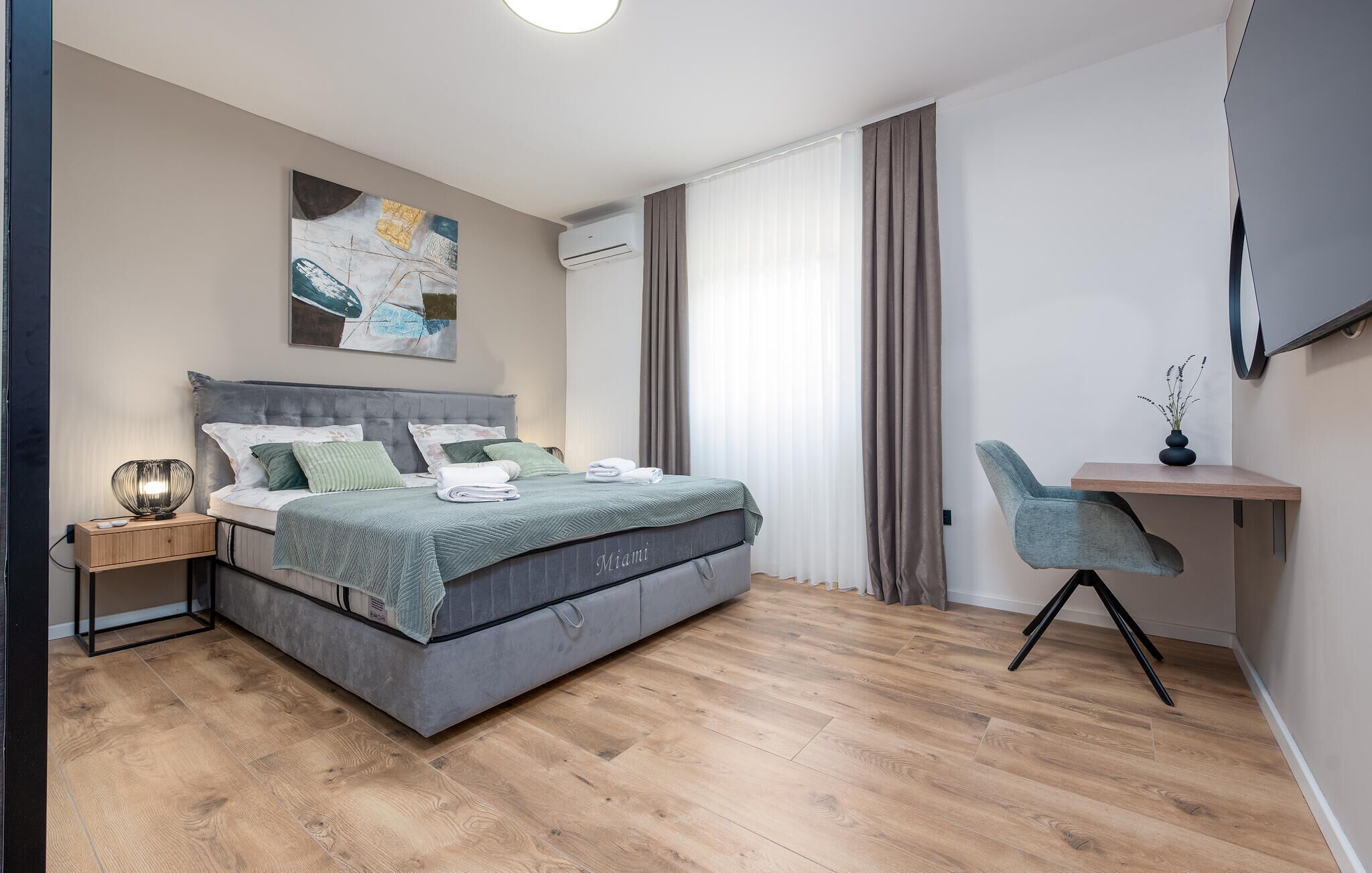 A modern bedroom with a bed, bedside table, and a desk with a chair.