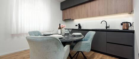 A modern kitchen with dark cabinets, a black countertop, and a wooden floor.
