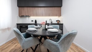 Une cuisine moderne avec des meubles de couleur sombre, une table de salle à manger ronde et des chaises bleu clair.