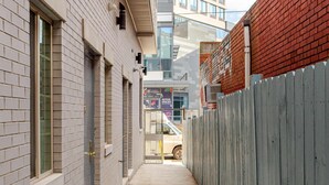Une ruelle étroite, avec un bâtiment en briques d’un côté et une clôture en bois de l’autre.
