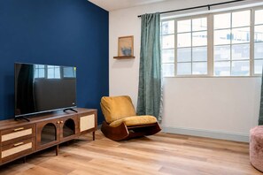 A room with a television on a wooden cabinet, a yellow chair, and a window with curtains. - Mins to Fishtown & Center City GlobeNest (Philadelphia)