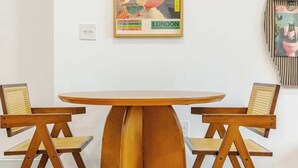 A dining table with a wooden base and four chairs, a framed poster on the wall, and a clock on the wall. - Mins to Fishtown & Center City | GlobeNest (Philadelphia)
