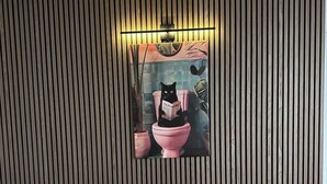 A modern bathroom with a striped wall design, a pink toilet, and a black cat reading a book. - Mins to Fishtown & Center City | GlobeNest (Philadelphia)