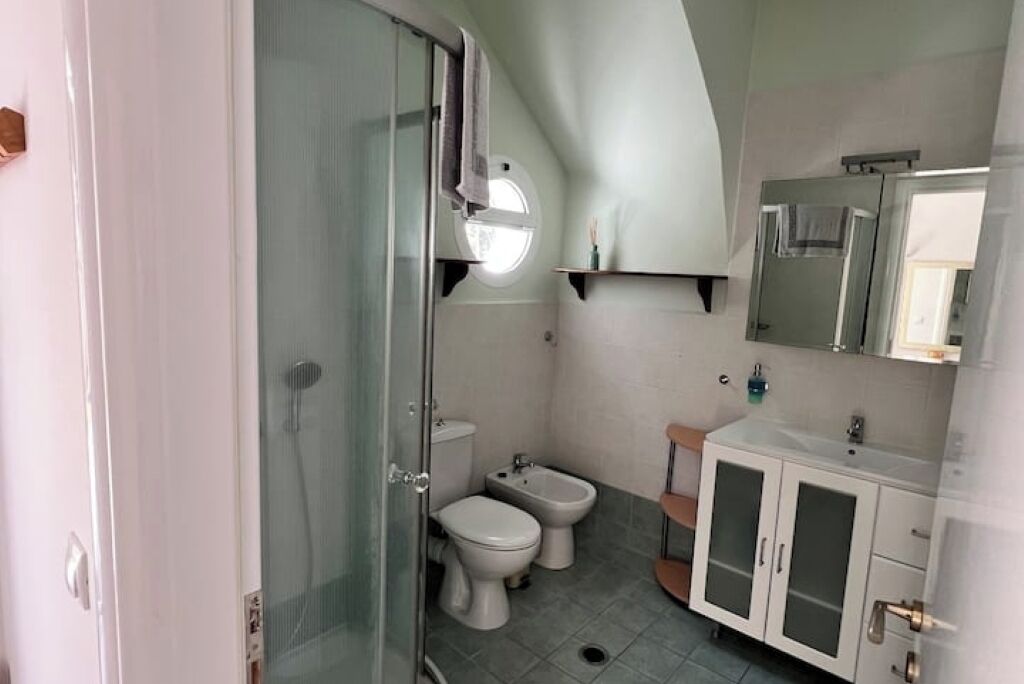 Une salle de bain dotée d’une douche à parois de verre, de toilettes, d’un bidet et d’un meuble-lavabo avec des placards.