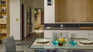 A modern kitchen with a glass dining table, wooden cabinets, and a view of the outdoors. - Family villa Keshi - not far from Tsilivi beach (Tragaki)