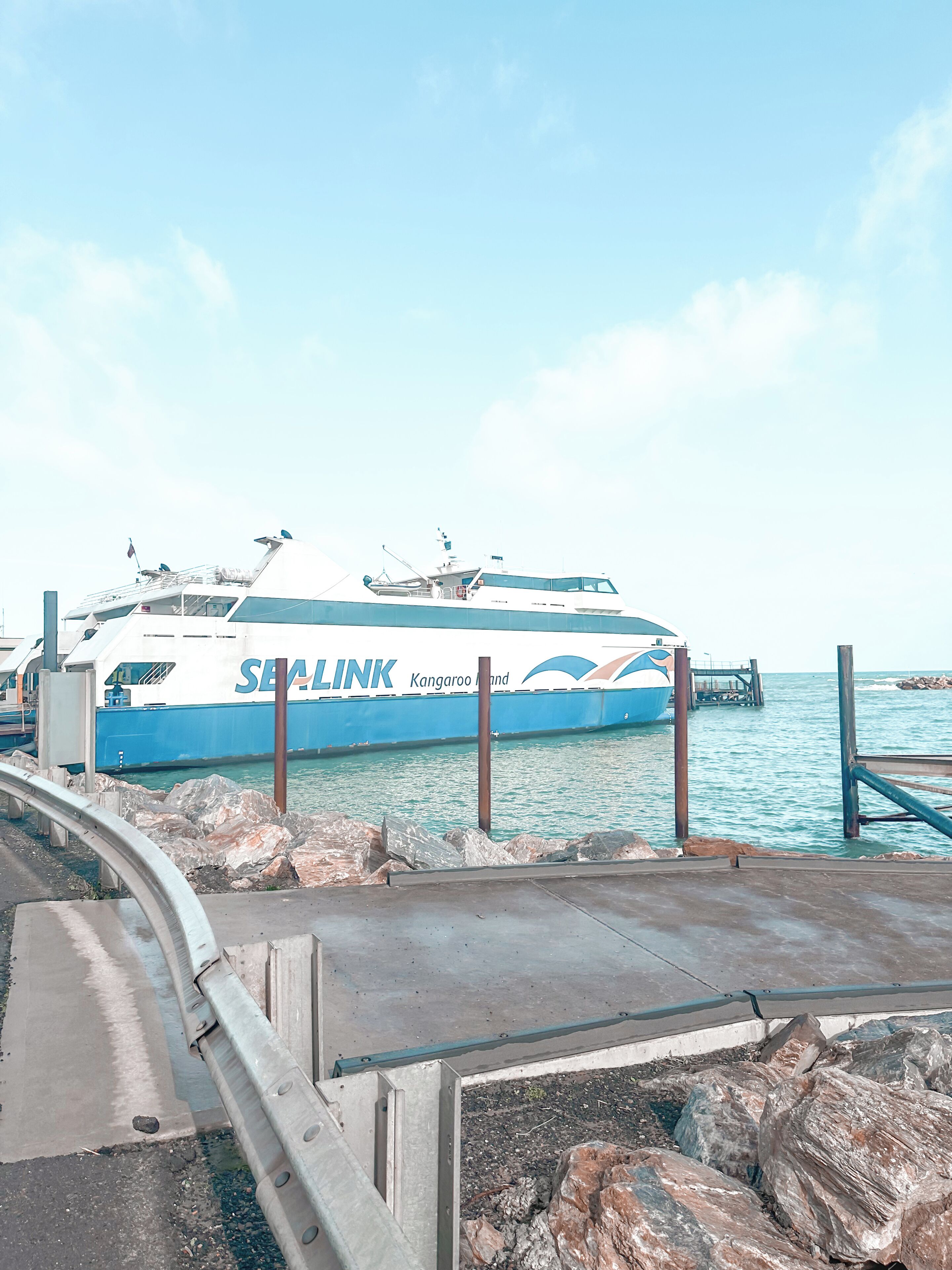 A ferry named 'SEALINK' docked at a pier with rocky terrain and clear skies.
