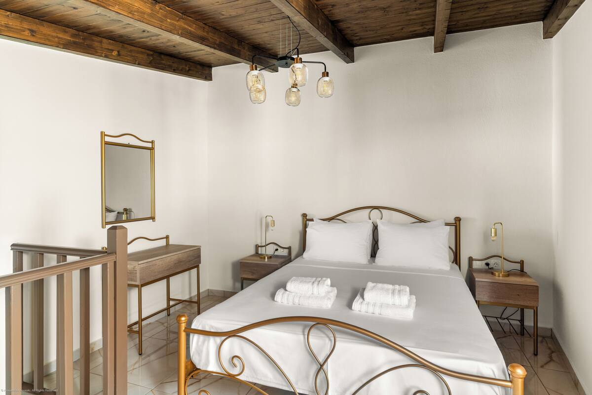 Une chambre à coucher avec un cadre de lit en bois, du linge de lit blanc, un bureau en bois, un miroir et un luminaire au plafond.