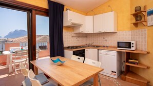 Une cuisine compacte avec des meubles blancs, un four à micro-ondes et un coin repas comprenant une table et des chaises en bois.