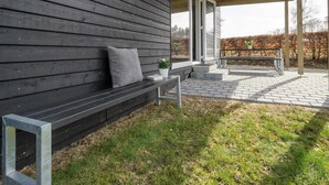 Un mur extérieur en bois, agrémenté d’un banc et d’une plante en pot.