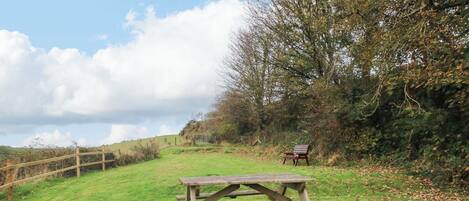 A picnic table in a grassy field with a bench in the background.