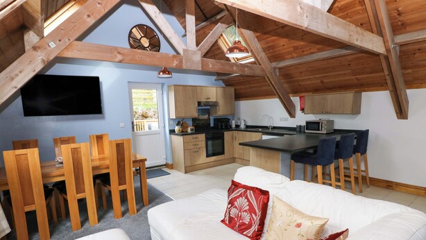 A cozy attic bedroom with a large bed, a dining area, and a kitchen. - Pendre Barn (Llanfyrnach)