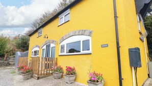 A yellow building with a wooden fence, potted flowers, and a sign reading "FENDRE BARN". - Pendre Barn (Llanfyrnach)