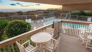 A wooden deck with a pool, chairs, and a table. - Direct Ocean Front 2BR w/ Pool (Nags Head)