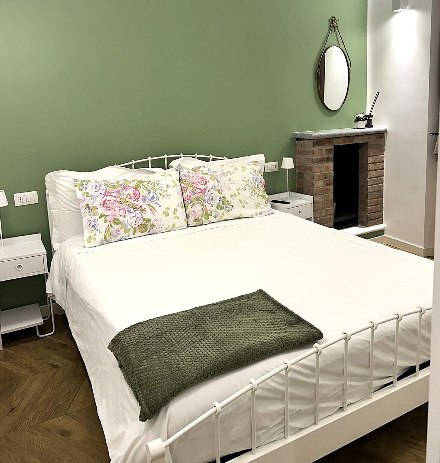 Une chambre à coucher comprenant un lit, deux tables de chevet, un miroir fixé au mur et une cheminée.