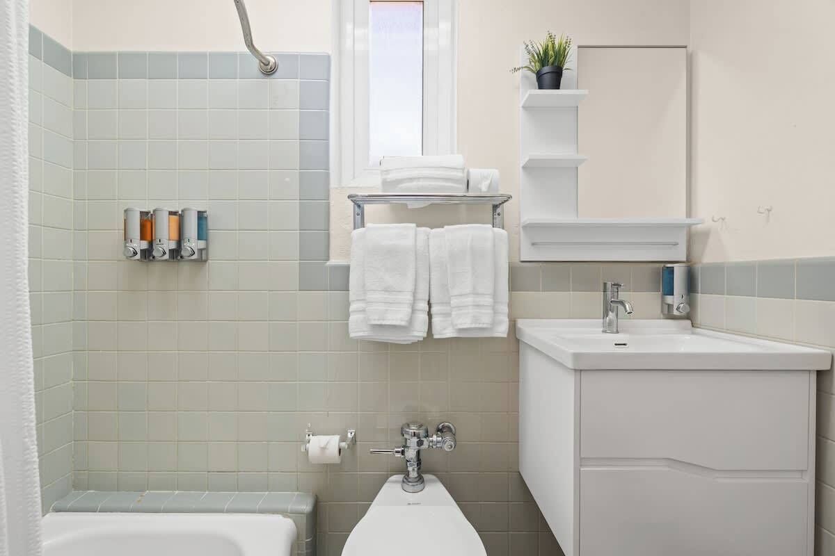 A bathroom with a bathtub, a sink, and a toilet. There are towels and toiletries on the wall.