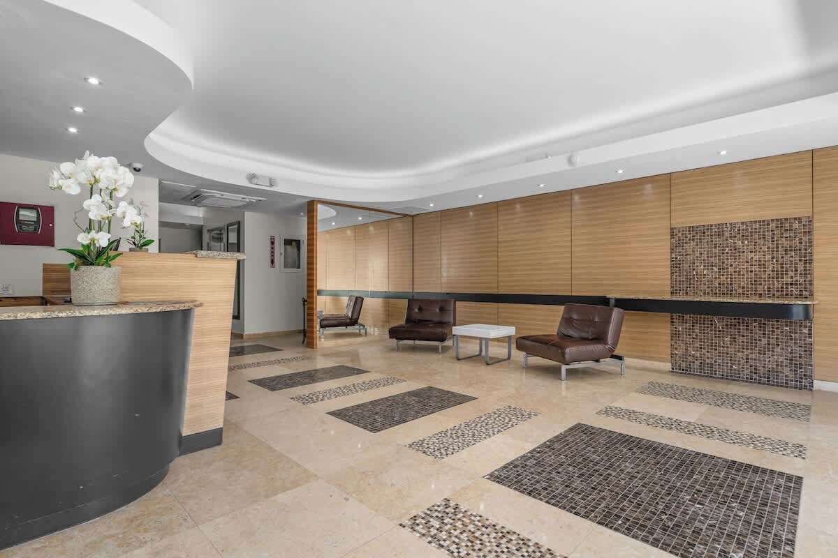 A modern reception area with a curved reception desk, seating area with leather chairs, and a decorative wall with a mosaic pattern.