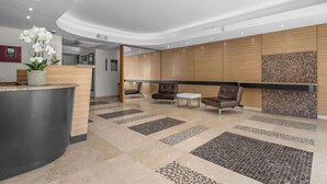 A modern reception area with a curved reception desk, seating area with leather chairs, and a decorative wall with a mosaic pattern.