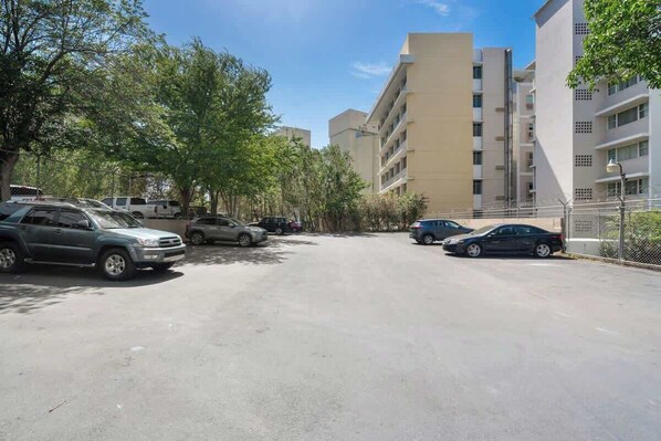 A parking lot with several cars, surrounded by trees and buildings.