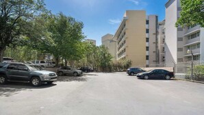 A parking lot with several cars, surrounded by trees and buildings.