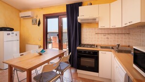 A compact kitchen with a dining area, a stove, oven, and a dishwasher.