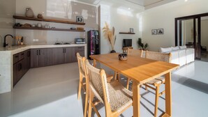 Une cuisine moderne avec des meubles en bois, une table à manger et des chaises en osier.