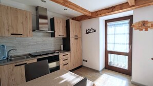 Eine moderne Küche mit Holzausstattung, einem eingebauten Herd und einem Fenster mit Blick auf ein Haus.
