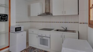 Una cucina compatta con mobili bianchi, un forno a microonde, un lavello e un forno.
