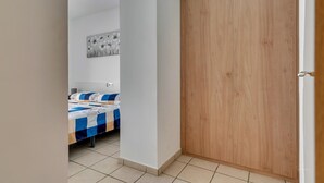 Un dormitorio con una cama, una puerta de madera y una obra de arte colgada en la pared.