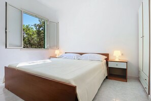 Una camera da letto con un letto, comodini, un armadio e una finestra con persiana aperta.