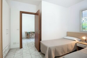 Un dormitorio con cama, mesita de noche y ventana.