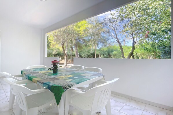 Un comedor con una mesa y sillas, vista a árboles, y una ventana.