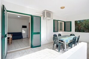Un espace repas comprenant une table et des chaises, un canapé et une porte coulissante donnant sur une autre pièce.