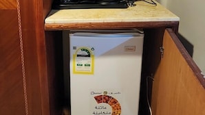 A compact kitchenette with a built-in refrigerator, a stove, and a small countertop. - Wefaq Al-Mashaer Hotel (Makkah)